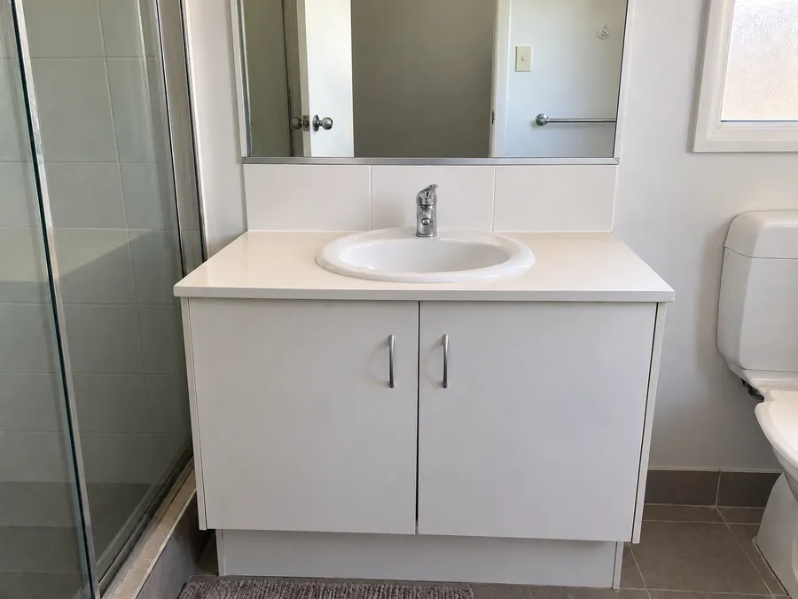 Clean bathroom vanity and clear mirror after a professional bond clean